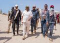 President Said Abdullahi Deni walking through deep sand with officials, elders and Puntland security during his tour of eastern Mudug