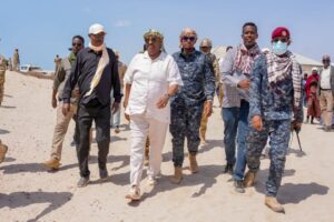 President Said Abdullahi Deni walking through deep sand with officials, elders and Puntland security during his tour of eastern Mudug