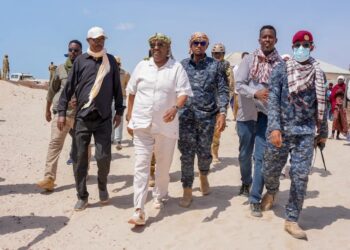 President Said Abdullahi Deni walking through deep sand with officials, elders and Puntland security during his tour of eastern Mudug