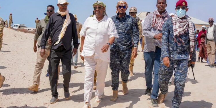 President Said Abdullahi Deni walking through deep sand with officials, elders and Puntland security during his tour of eastern Mudug